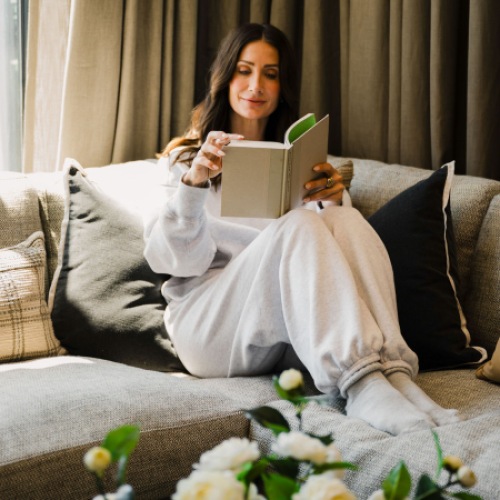 a woman laying on a couch reading