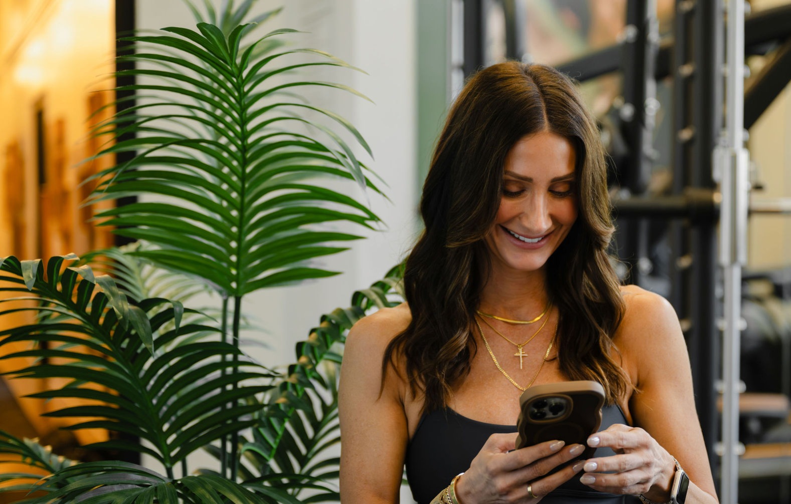 Resident Perks woman smiling at mobile phone at gym