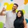 a young couple takes a picture in front of a wall painted with hearts