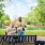 woman on park bench talking to man with a dog on a leash