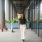 woman walks along a building with parked scooters